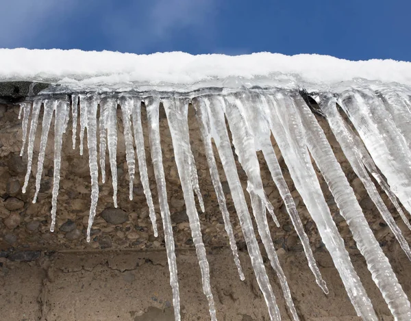 Nagy jégcsapok lógnak a ház tetején tavasszal — Stock Fotó