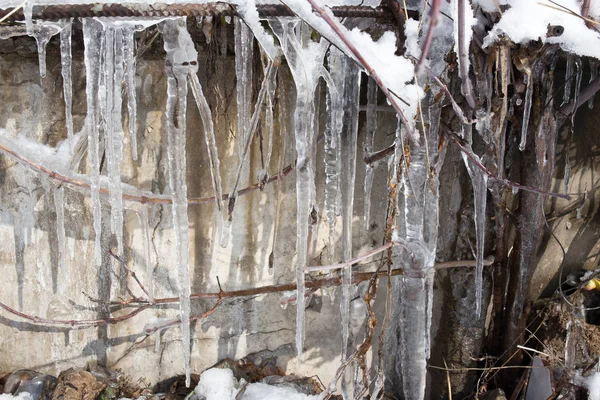 Large icicles hanging on the roof of the house in springtime — Stock Photo, Image