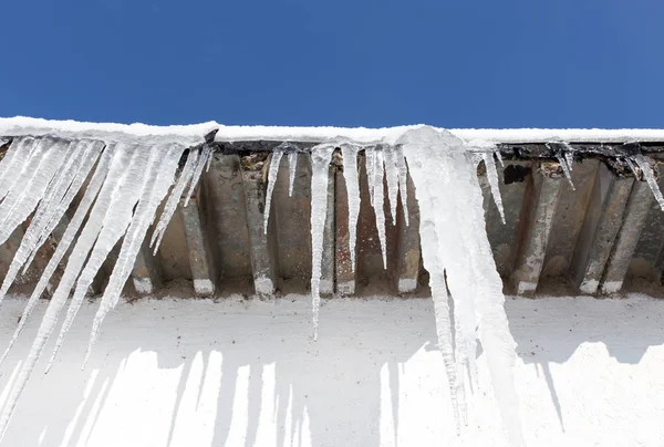 Nagy jégcsapok lógnak a ház tetején tavasszal — Stock Fotó