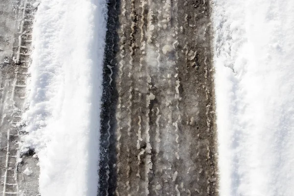 Rastro del coche en la nieve con asfalto —  Fotos de Stock