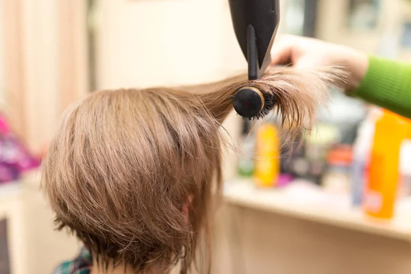 Cabeleireiro seca o cabelo loiro secador — Fotografia de Stock