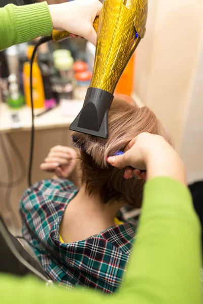 Парикмахер сушит светлые волосы — стоковое фото