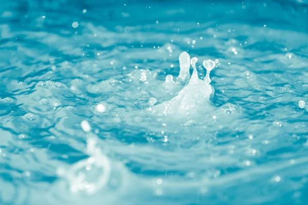 Gocce d'acqua che cadono in acqua blu — Foto Stock