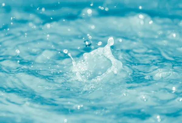 Vanndråper som faller i blått vann – stockfoto