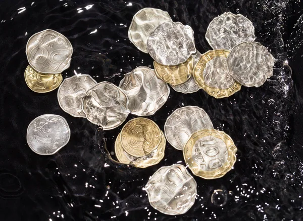 Monete in schizzi d'acqua su sfondo nero — Foto Stock