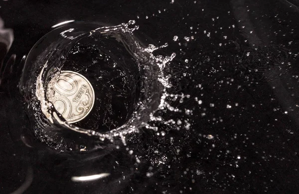 Κέρματα σε νερό πιτσιλιές πάνω σε μαύρο φόντο — Φωτογραφία Αρχείου