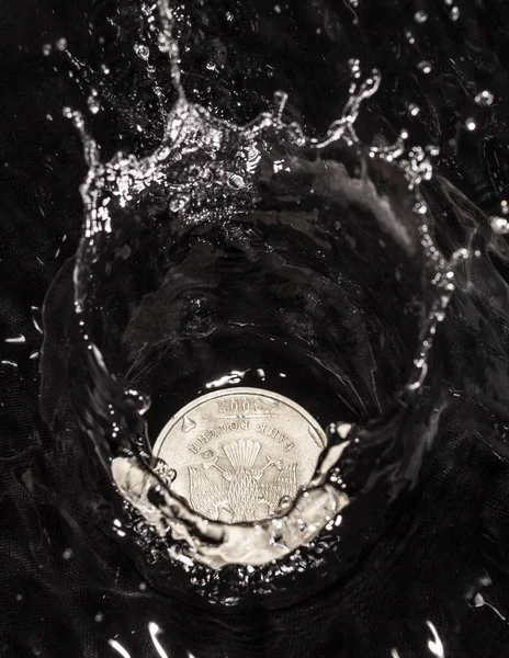 Monete in schizzi d'acqua su sfondo nero — Foto Stock