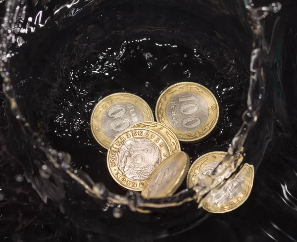 Монеты в воде брызги на черном фоне — стоковое фото