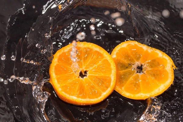 Pomarańczowy w wodzie rozpryski na czarnym tle — Zdjęcie stockowe