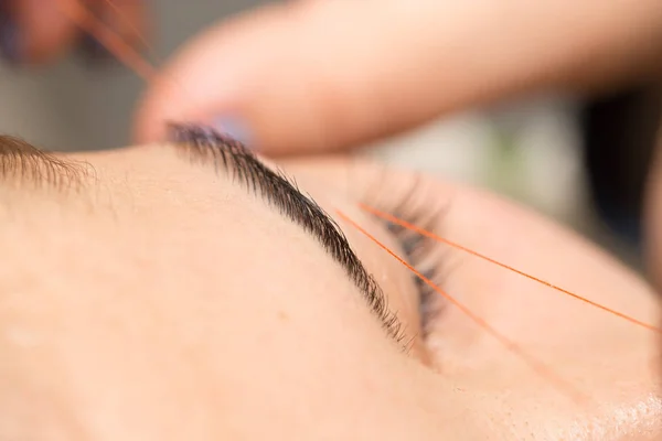 Grooming the eyebrows thread in a beauty salon. close — Stock Photo, Image