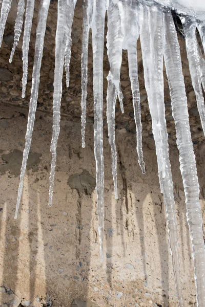 Large icicles hanging on the roof of the house in springtime — Stock Photo, Image