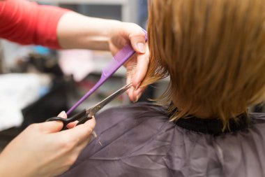 Güzellik salonunda makas kesen bir kadın.