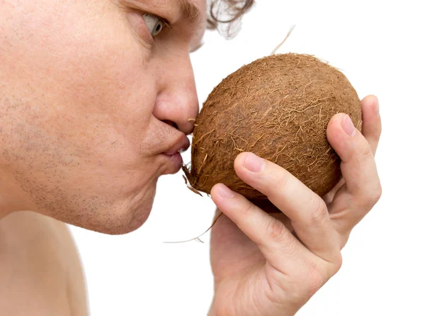 Um homem quer comer um coco em um fundo branco — Fotografia de Stock