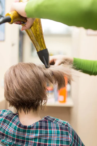 Cabeleireiro seca o cabelo loiro secador — Fotografia de Stock