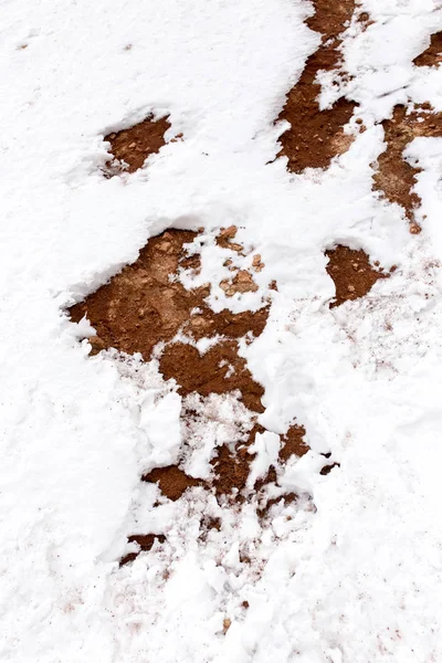 Snö på röd lera i naturen — Stockfoto