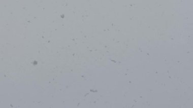 Kar gri gökyüzü arka plan olarak uçar.