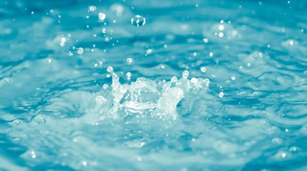 Gocce d'acqua che cadono in acqua blu — Foto Stock