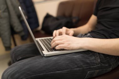 Dizüstü bilgisayarda çalışan genç bir adam.