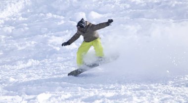 İnsanlar kışın karda snowboard yapıyor.