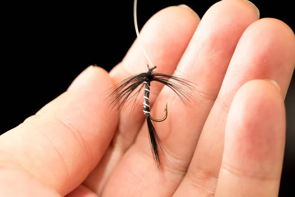 Fly to catch fish in a hand on a black background — Stock Photo, Image