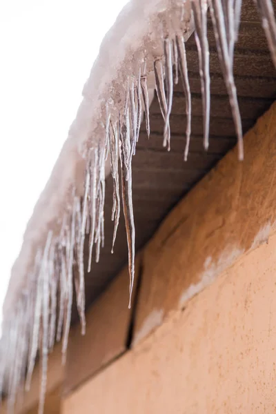 Icicles em um telhado de uma casa no inverno — Fotografia de Stock