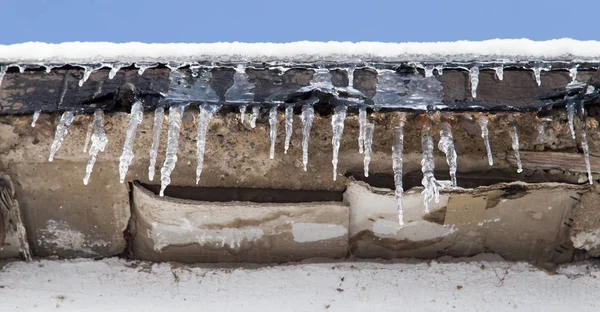 Сосульки на крыше дома зимой — стоковое фото