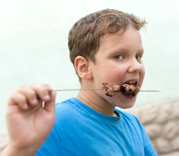 Хлопчик їсть шашлик на паличці — стокове фото