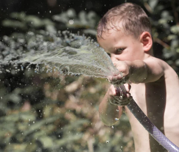ホースから水を噴き出す少年 自然公園で — ストック写真