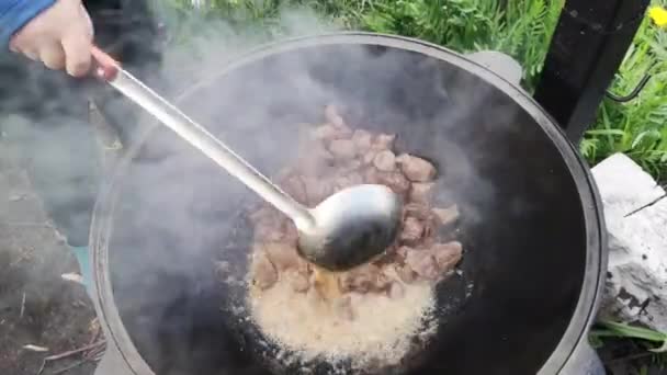 在花园的大锅里准备肉酱的妇女的特写镜头 — 图库视频影像