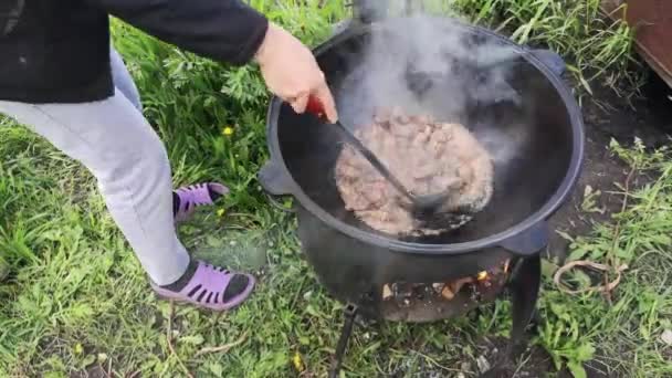 在花园的大锅里准备肉酱的妇女的特写镜头 — 图库视频影像