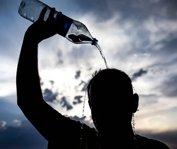 日落时 人把水泼洒在头上 — 图库照片