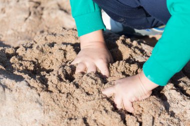 Çocuk kumda oynuyor. Doğadaki parkta.