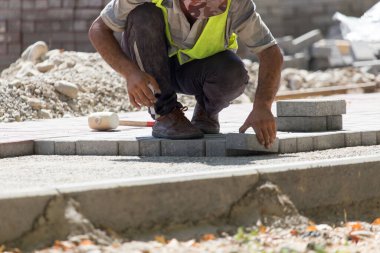 İşçi yola kaldırım taşı koyar .