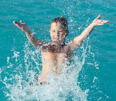 Çocuk su parkında su sıçratarak yüzüyor. .