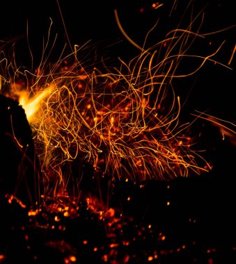 Siyah arkaplanda kıvılcımlar saçan ateş .