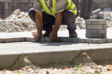 İşçi yola kaldırım taşı koyar .