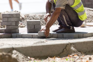 İşçi yola kaldırım taşı koyar .