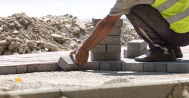 İşçi yola kaldırım taşı koyar .