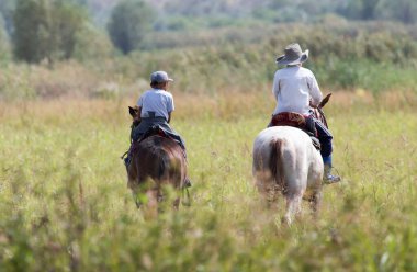 Doğada ata binen iki çocuk .
