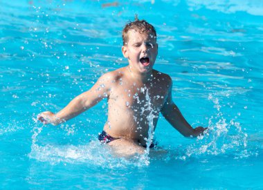 Çocuk su parkında su sıçratarak yüzüyor. .