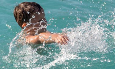 Çocuk su parkında su sıçratarak yüzüyor. .