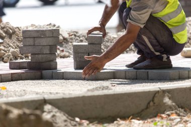 İşçi yola kaldırım taşı koyar .