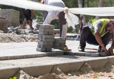 İşçi yola kaldırım taşı koyar .