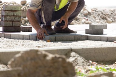 İşçi yola kaldırım taşı koyar .