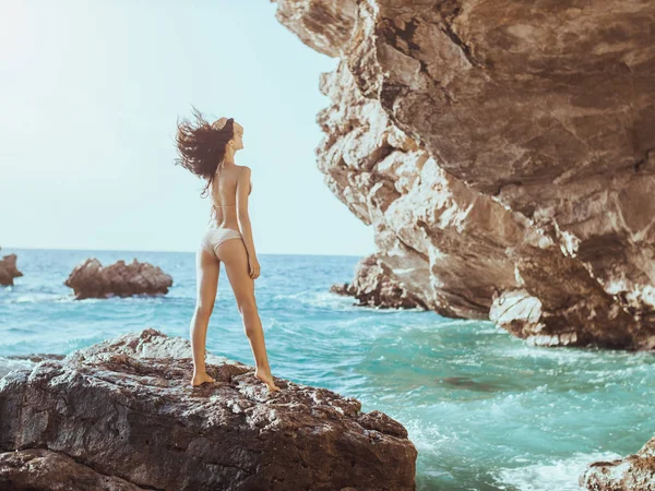 Gyönyörű fiatal nő, a vad, sziklás strand. — Stock Fotó