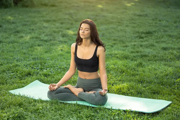 Ung flicka gör yoga i parken — Stockfoto