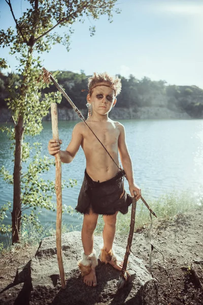 Caveman, manly boy with stone axe and bow hunting outdoors — Stock Image Caveman, manly boy with stone axe and bow hunting outdoors Royalty Free Stock Photos
