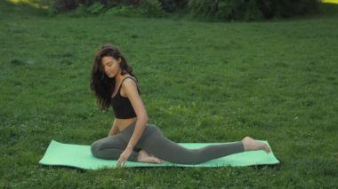 Dışarıda parkta yoga yapan bir kadın.