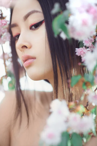 Retrato de una hermosa chica asiática al aire libre contra el árbol de flores de primavera . — Foto de Stock