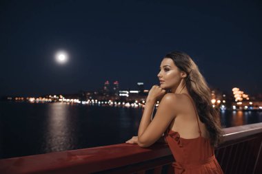 Gece şehir arka plan binalar üzerinde duran genç ellegant kadın. Özgürlük ve aşk kavramı kız